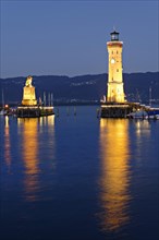 Illuminated Bavarian lion and the lighthouse at dusk