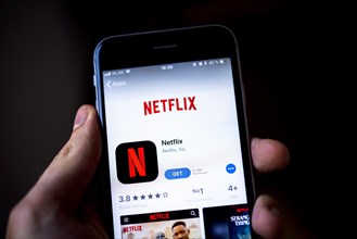 Hand holding iPhone with Netflix App in the Apple App Store