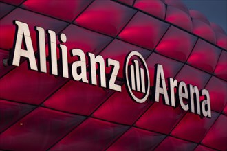 Red illuminated Allianz Arena with lettering