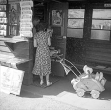 Woman with pram looks after newspapers