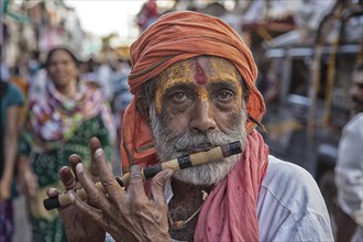 Sadhu plays flute at hinduistic festival Kumbh Mela