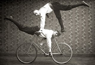 Two acrobats by bicycle