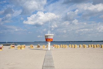 Empty sandy beach with DLRG monitoring tower and beach chairs