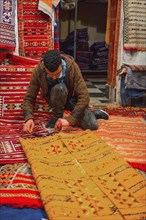 Carpet dealer folds a Moroccan carpet