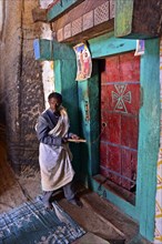 Priest at the door to the rock church Medhane Alem of Adi Kasho