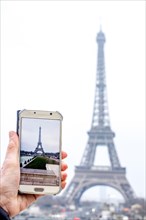 Woman photographing the Eiffel Tower with her smartphone