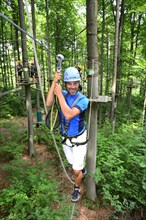 Man climbs in the high wire park of the forest adventure center and climbing forest Riegling
