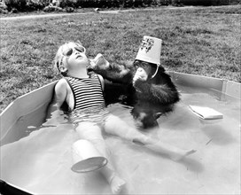 Girl with monkey sitting relaxed in the swimming pool and bathing in the sun
