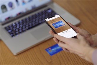 Woman with iPhone X smartphone in her hand scanning a credit card with Apple Pay