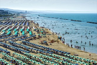 Overcrowded touristic bathing beach with umbrellas