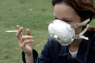 Smoking woman wearing respiratory mask
