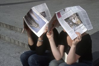 Young people with newspapers above their heads