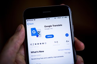 Hand holding iPhone with Google Translate App in the Apple App Store