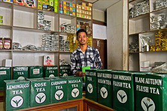 Tea merchant behind large tins with tea in his shop
