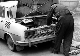 Man repairing car after instruction ca. 1970s