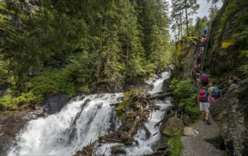 Hikers on the alpine path through the Hollschlucht gorge with waterfall