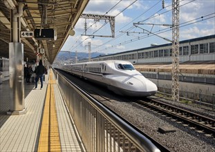 Shinkansen high-speed train travels through Mishima Station