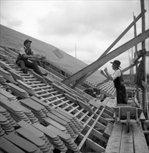Two roofers throw themselves on a house tile to around 1950