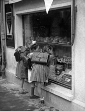 School children are standing in front of a shop window