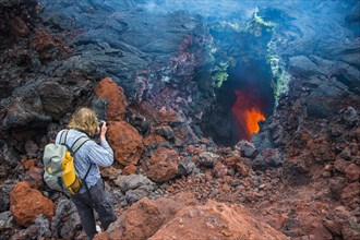 Tourist photographing an active magma stream below the Tolbachik volcano