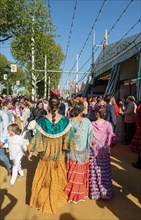 Spanish women with colorful flamenco dresses in front of marquees