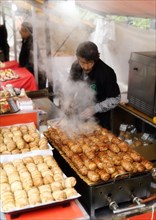 Street food vendor selling grilled bacon wrapped rice balls