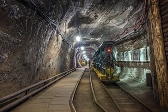 Yellow passenger underground train used in an old salt mine to transport tourists