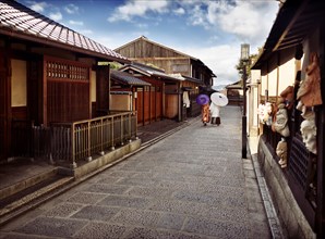 Couple with Japanese parasols wearing traditional kimono walking down an old street Yasaka dori