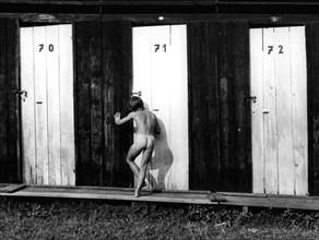 Naked child looks through door ca. 1970s