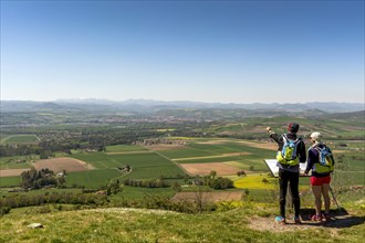 Hikers enjoying the view from Usson village on plain of Limagne and the volcanic landscape of the Chaine des Puys