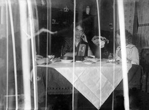 Family sitting at the dining table behind a curtain