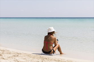 Woman sitting down by the sandy beach