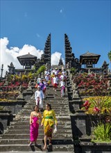 Balinese believers in traditional clothing go down stairs