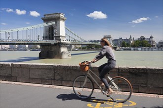 Cyclist on the bank of the Danube with Szechenyi Chain Bridge