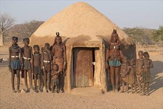 Himba women and children in front of a mud hut