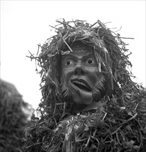 Masked man with drooping corner of his mouth and a suit of straw