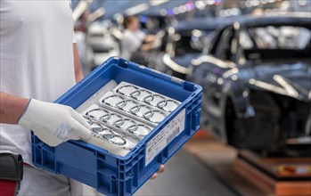 An Audi employee holds a box of Audi logos on the Audi A4 assembly line at the Audi AG plant in Ingolstadt