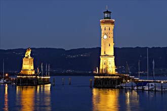 Illuminated Bavarian lion and the lighthouse at dusk