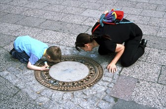 Mother and child looking in manhole cover