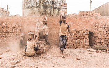 Workers with bricks on their heads in the brickyard