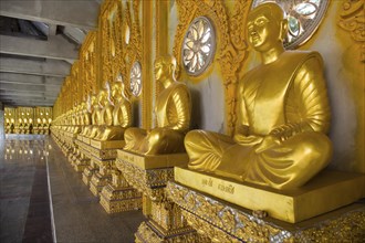 Row of golden Buddha statues in the corridor of the Phra Maha Chedi Chai Mongkhon Pagoda