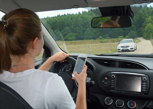 Young woman using a mobil phone while she drive a car