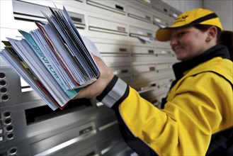 Postwoman distributes letters on mailboxes