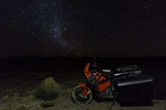 Heavily packed motorcycle on the plateau in front of the starry sky