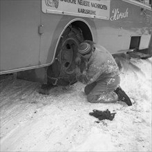 Man repairing the tyre of a bus around 1950 in winter