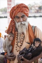 Sadhu with monkeys in his arm