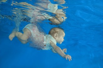 Infant girl dives in a pool