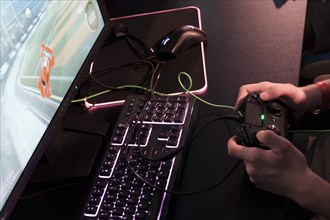 Hands of a player operate game controller over a keyboard