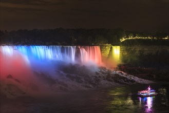 Tourist boat in front of illuminated waterfall