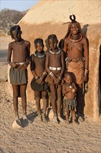 Himbafrau with children in front of a mud hut